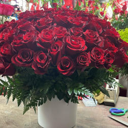 Large bouquet of red roses in a white vase with fern foliage
