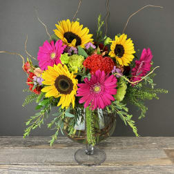 Bright mixed bouquet with sunflowers and pink gerbera daisies in a glass vase