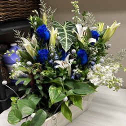 Blue roses and white lilies arranged in a rectangular wooden planter