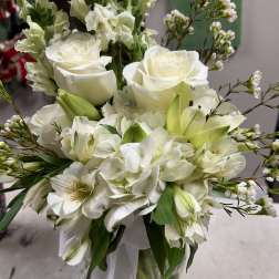 White floral bouquet with roses, lilies, and hydrangeas in a glass vase
