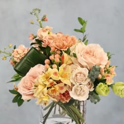 Peach and cream bouquet in a clear square vase