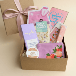 Gift box with assorted beauty items and a pink ribbon