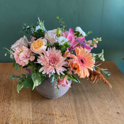 Mixed pink and peach flowers arranged in a gray vase