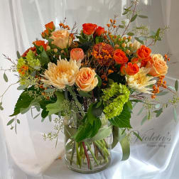 Orange and peach roses with cream chrysanthemums in a glass vase