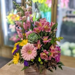 Mixed floral arrangement in a wooden box with pink and yellow blooms