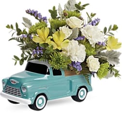 Bouquet of white and yellow flowers arranged in a turquoise toy truck