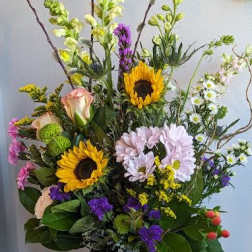 Mixed bouquet with sunflowers, daisies, and roses in a tall vase