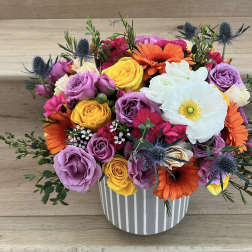 Colorful bouquet of roses, gerbera daisies, and a white anemone in a striped vase