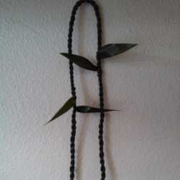 Black braided hanging cord with small green leaves on a wall