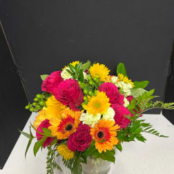 Mixed bouquet of pink roses and yellow-orange gerbera daisies in a glass vase