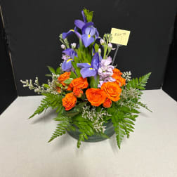 Orange roses and purple irises arranged in a low vase