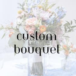 Pastel bouquet with roses, daisies, and blue flowers in a clear vase