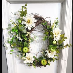 White floral wreath with green apples and mixed greenery on a twig base