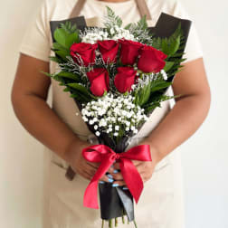 Bouquet of red roses with white baby's breath wrapped in black paper and tied with a red ribbon