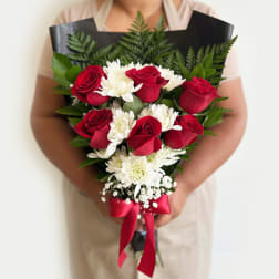 Bouquet of red roses and white daisies wrapped in black paper