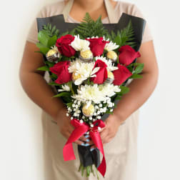 Bouquet of red roses, white daisies, and chocolates wrapped in black paper