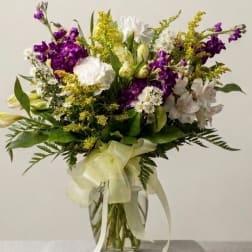 Mixed bouquet of purple, white, and yellow flowers in a glass vase