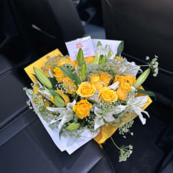 Yellow roses and white lilies in a wrapped bouquet