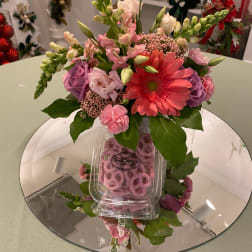 Pink and purple mixed bouquet with a coral gerbera daisy in a clear container.