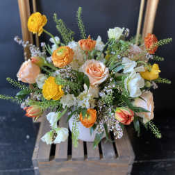 Mixed bouquet of peach, yellow, and white flowers in a white vase