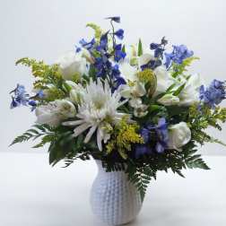 White and blue mixed flower arrangement in a textured white vase