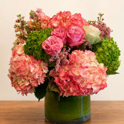 Pink hydrangeas and roses arranged in a green glass vase