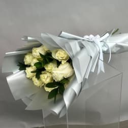 Bouquet of cream roses wrapped in silver paper with a white ribbon