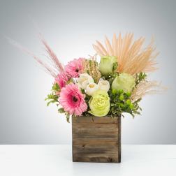 Pink and white flowers arranged in a wooden box with dried accents