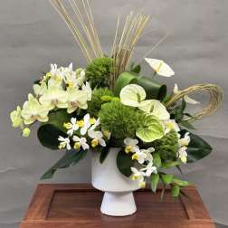 White and green floral arrangement in a white pedestal vase