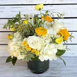White and yellow flower arrangement in a dark glass vase