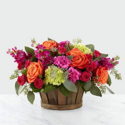 Orange and pink roses arranged in a wooden basket