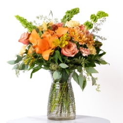 Orange and peach mixed flower bouquet in a clear glass vase