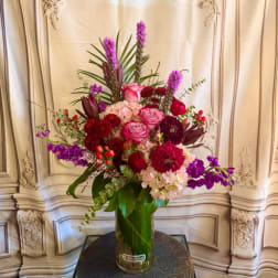 Tall mixed bouquet in a glass vase with pink, red, and purple flowers