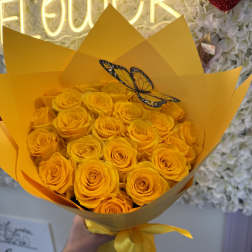 Bouquet of yellow roses wrapped in bright yellow paper with a butterfly decoration