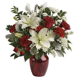 Red roses and white lilies arranged in a red glass vase