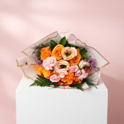 Bouquet of orange and pink roses wrapped in white paper