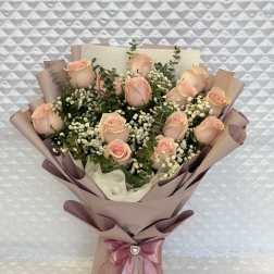 Bouquet of pale pink roses wrapped in blush paper with a satin ribbon