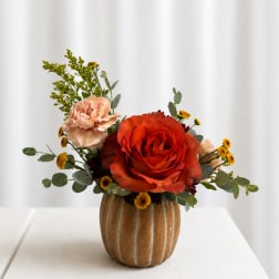 Orange rose and peach carnation arrangement in a brown vase