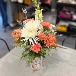 Mixed bouquet of white and coral flowers in a patterned vase