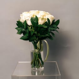 White rose bouquet in a clear glass vase with a ribbon