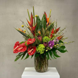 Tropical flower arrangement in a glass vase with red anthuriums and purple orchids