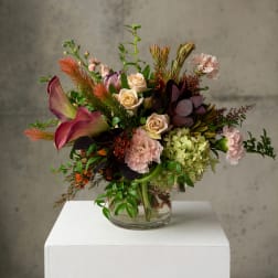 Mixed bouquet with roses, calla lilies, and carnations in a clear glass vase