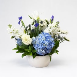 Blue and white floral arrangement in a white bowl vase