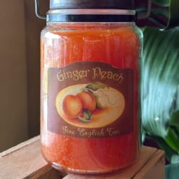 Orange candle in a glass jar labeled Ginger Peach