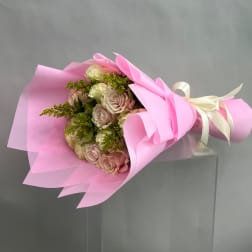 Pink and cream rose bouquet wrapped in pink paper with a ribbon