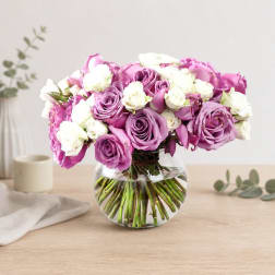 Pink and white roses arranged in a clear glass vase