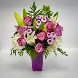 Pink roses and white lilies arranged in a purple vase