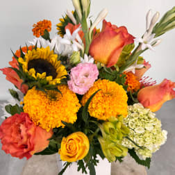 Colorful bouquet with roses, sunflowers, marigolds, and white lilies in a vase