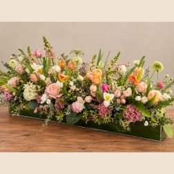 Low rectangular floral arrangement with pink, peach, white, and orange blooms