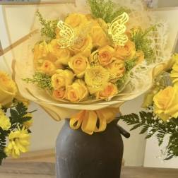 Yellow rose bouquet wrapped in cream paper with butterfly accents